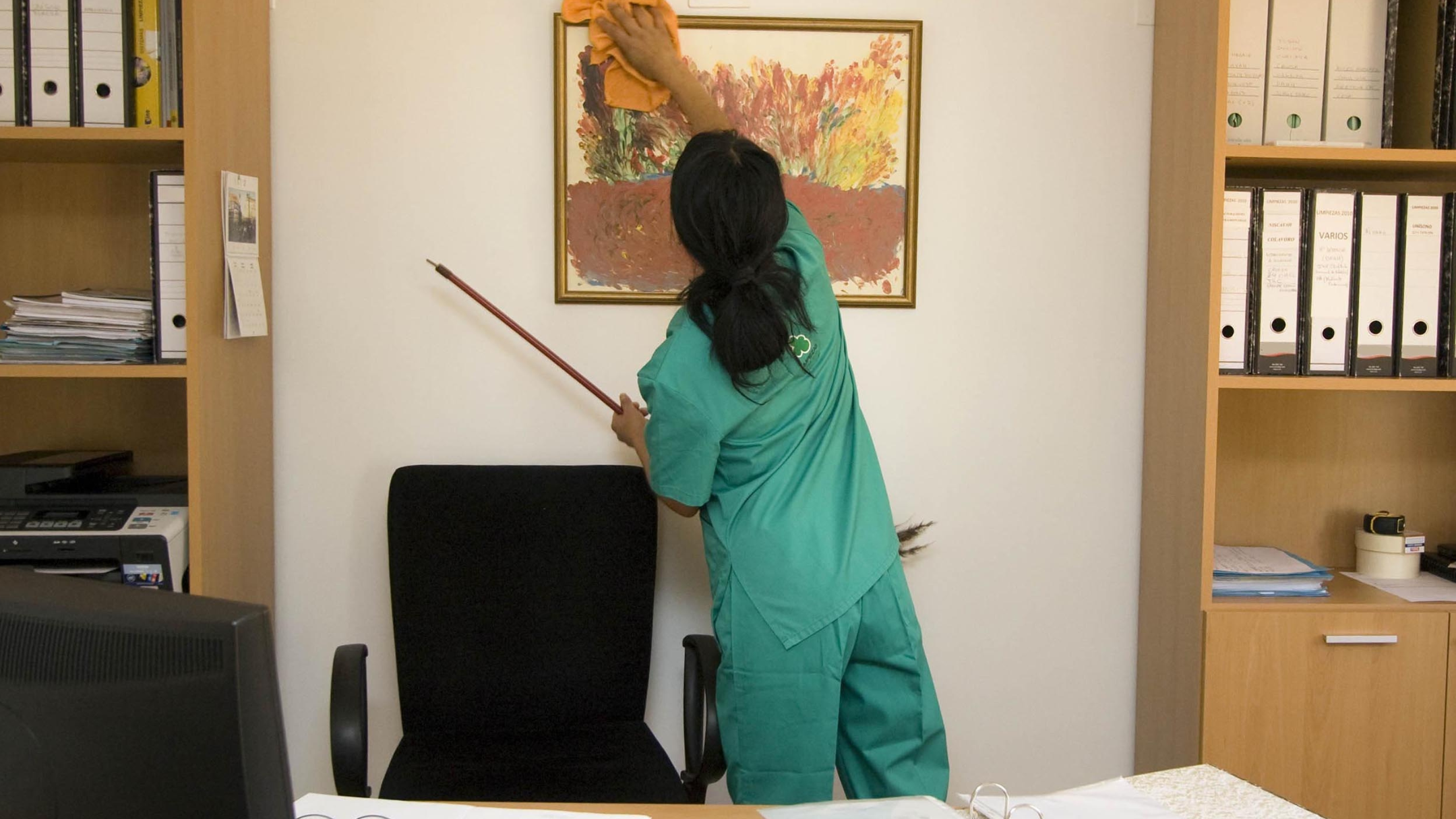 Maid cleaning a wall frame