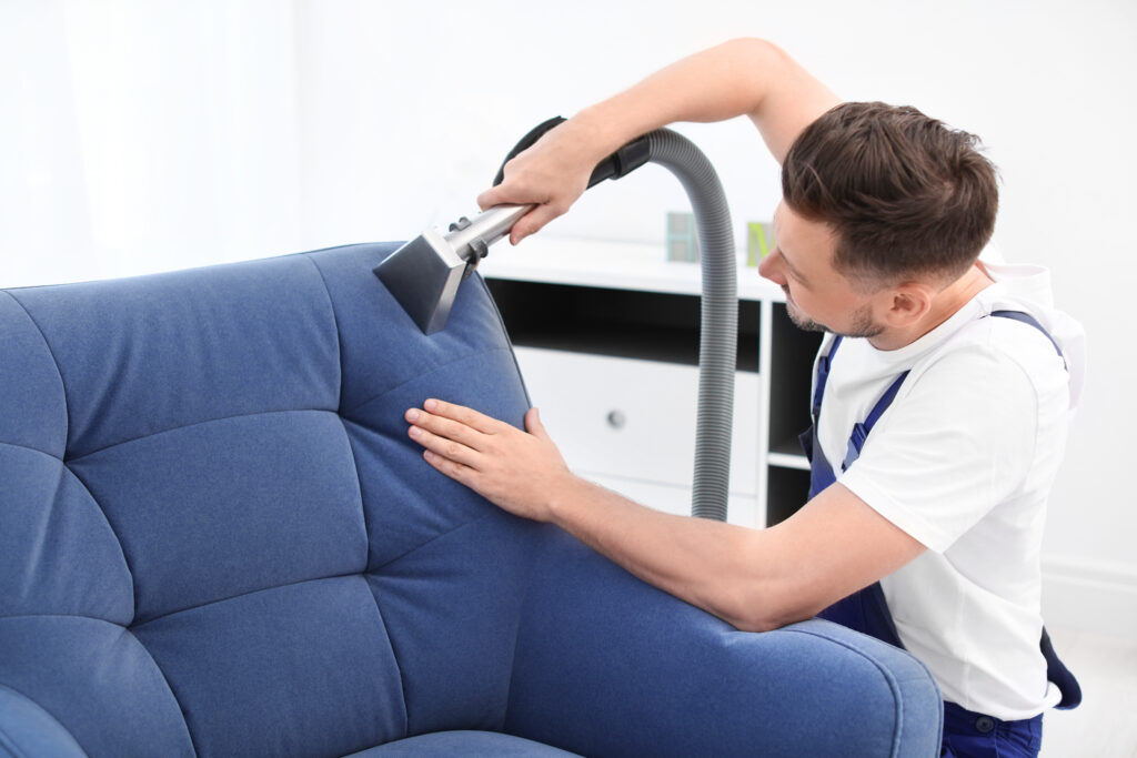 Dry cleaning worker removing dirt from armchair indoors recurring service