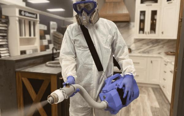 Cleaner with full PPE equipment doing disinfection service